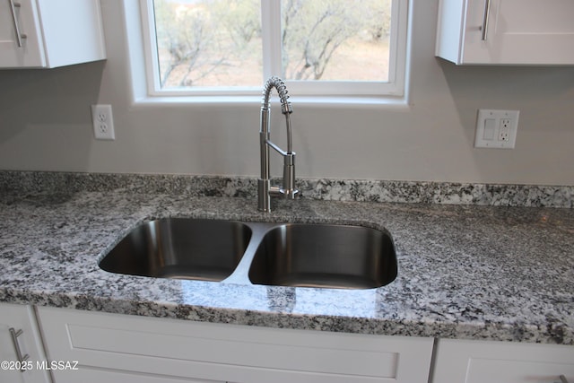 room details with light stone counters, white cabinets, and a sink