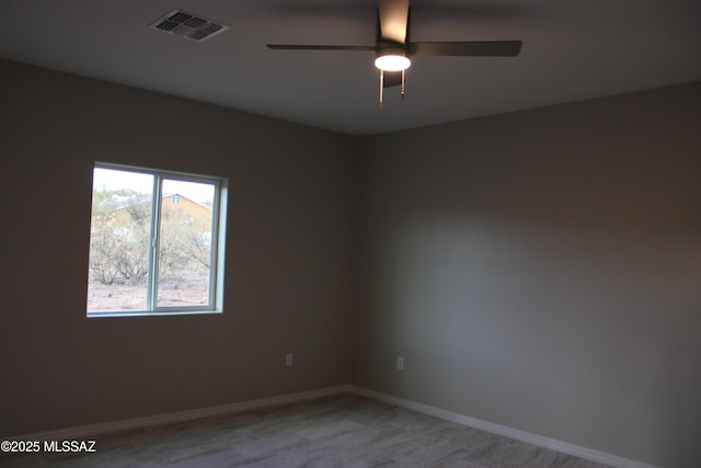 empty room featuring light wood-type flooring, visible vents, ceiling fan, and baseboards