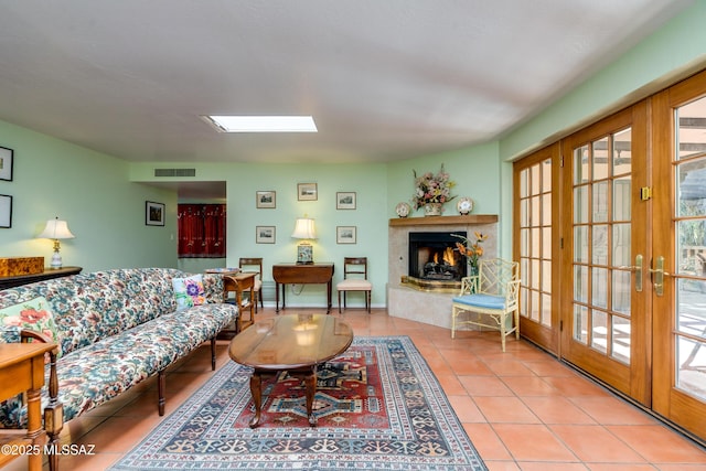 living room featuring light tile patterned floors, a skylight, and french doors