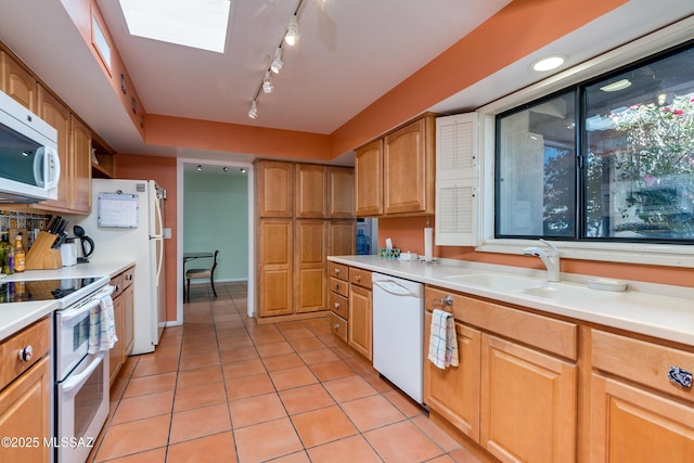 kitchen with sink, white appliances, light tile patterned floors, and a skylight