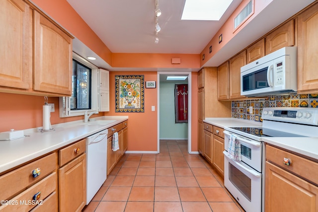 kitchen featuring decorative backsplash, sink, white appliances, a skylight, and track lighting