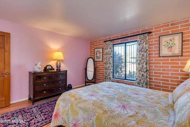 bedroom with brick wall and wood-type flooring