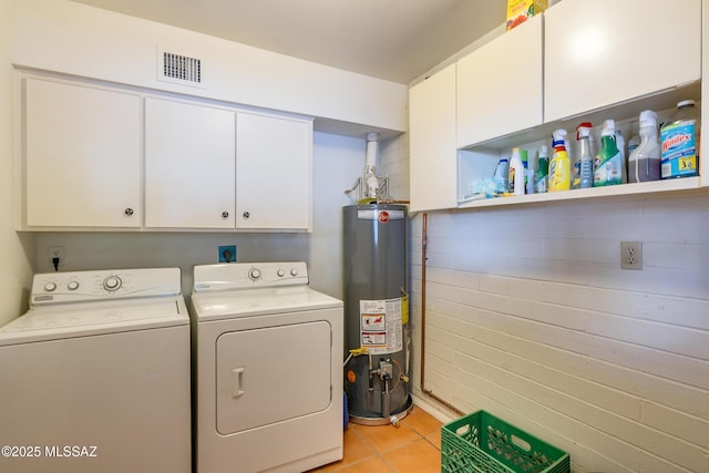 laundry area with water heater, cabinets, light tile patterned flooring, and washing machine and clothes dryer