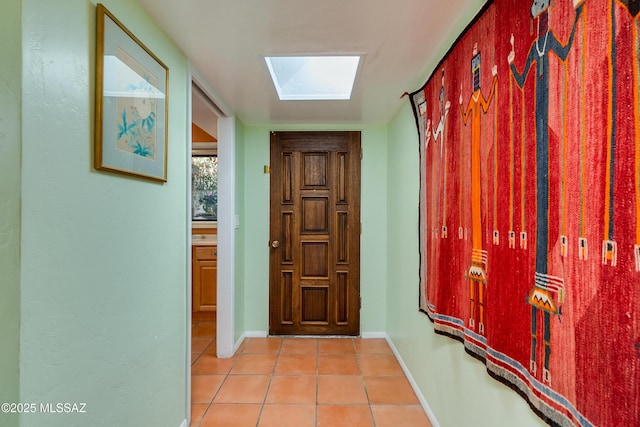 doorway to outside with a skylight and light tile patterned flooring