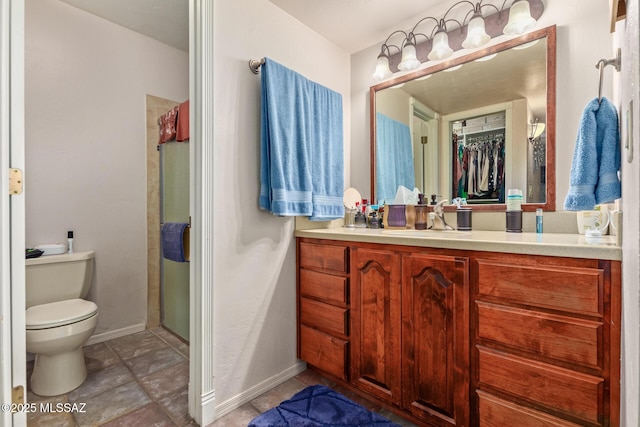 bathroom featuring toilet, vanity, and a shower with door