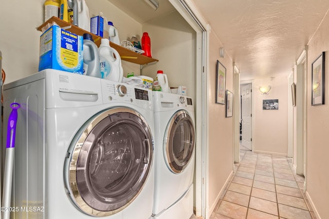 clothes washing area featuring washer and dryer, a textured ceiling, and light tile patterned floors