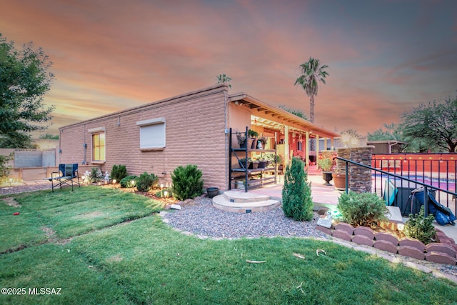 property exterior at dusk with a patio area and a yard