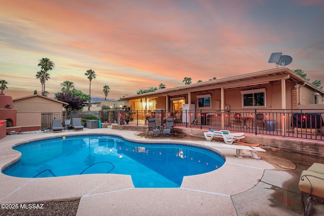 pool at dusk with a patio area