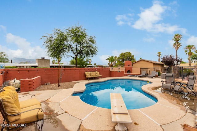 view of pool with a patio area, a mountain view, and a diving board