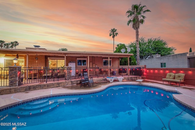 pool at dusk with a patio area