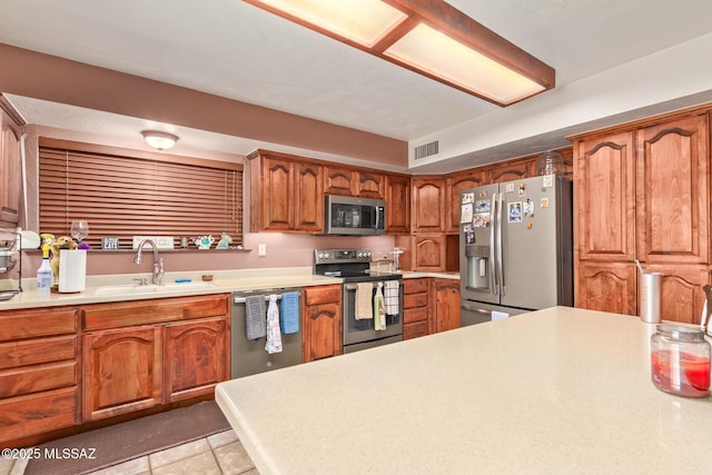 kitchen with sink, light tile patterned floors, and stainless steel appliances