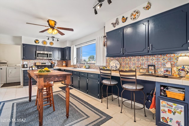 kitchen with sink, separate washer and dryer, decorative backsplash, light tile patterned flooring, and appliances with stainless steel finishes