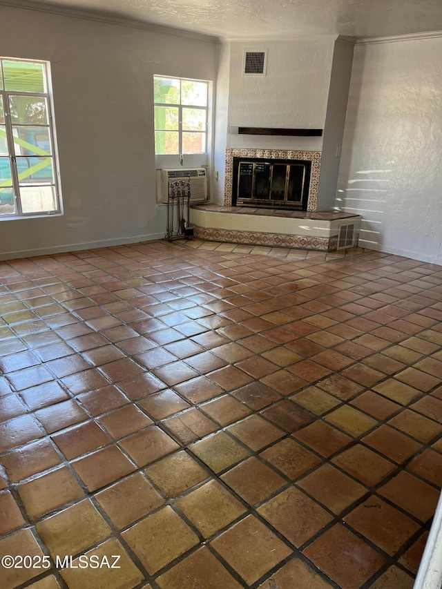 unfurnished living room with a textured ceiling, cooling unit, and a fireplace