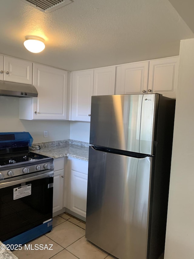 kitchen featuring stainless steel fridge, black stove, a textured ceiling, white cabinets, and light tile patterned flooring