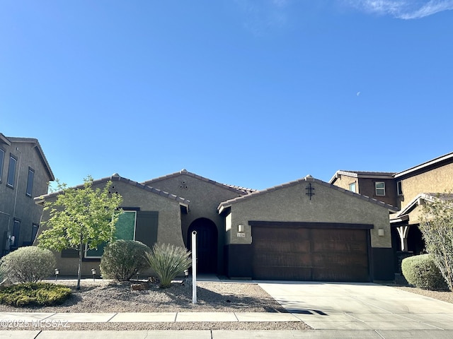 ranch-style house featuring stucco siding, an attached garage, a tile roof, and driveway
