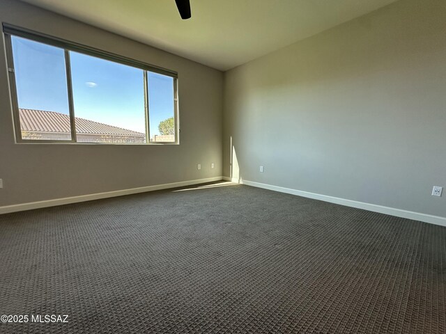 unfurnished room featuring baseboards, dark colored carpet, and ceiling fan