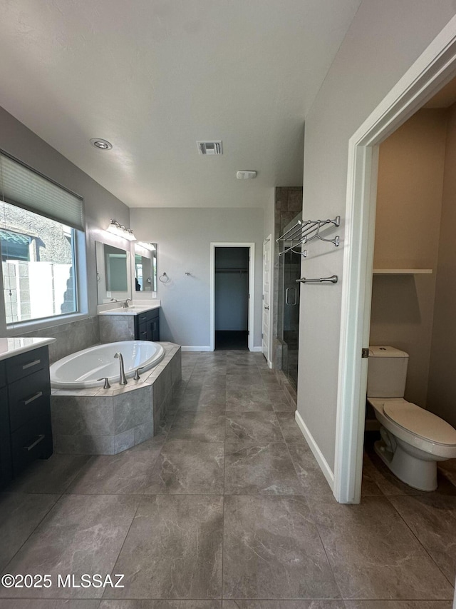 full bathroom with visible vents, baseboards, vanity, a stall shower, and a garden tub