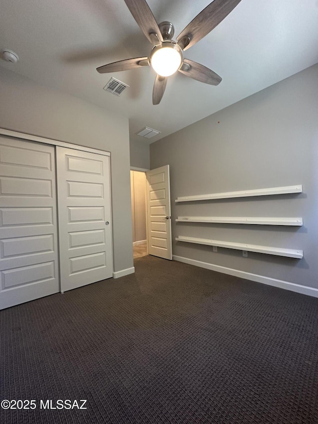 unfurnished bedroom featuring dark colored carpet, baseboards, ceiling fan, visible vents, and a closet