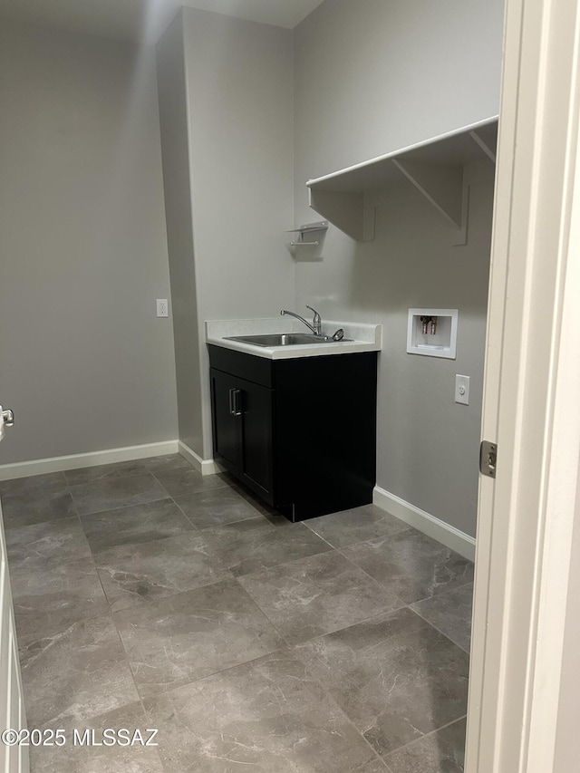 clothes washing area with baseboards, a sink, laundry area, and hookup for a washing machine