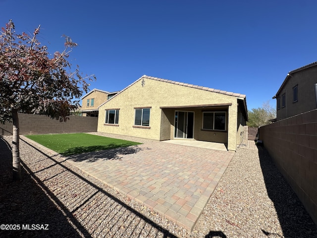 rear view of house with a fenced backyard, stucco siding, a patio area, and a yard