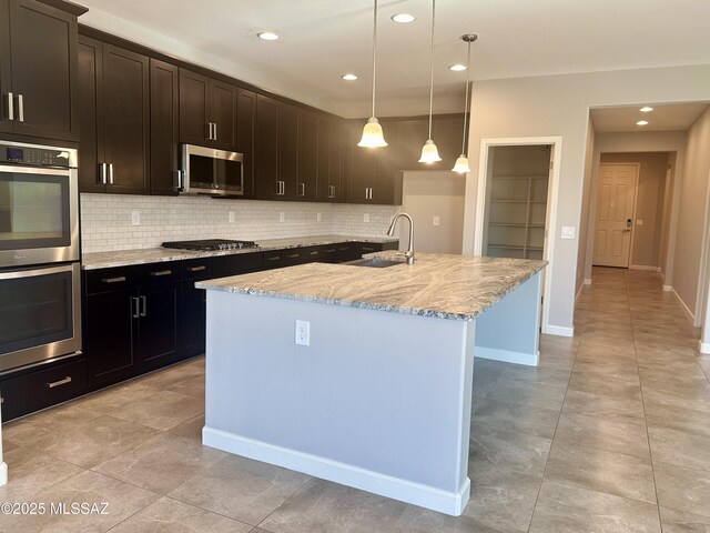 kitchen featuring backsplash, a sink, appliances with stainless steel finishes, and light stone counters