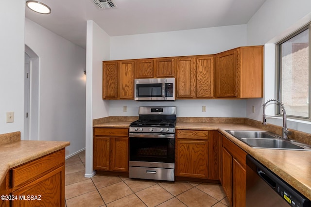 kitchen with light tile patterned flooring, stainless steel appliances, and sink