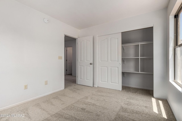 unfurnished bedroom with light carpet and a closet