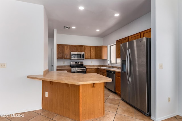 kitchen with sink, stainless steel appliances, kitchen peninsula, a kitchen bar, and light tile patterned floors