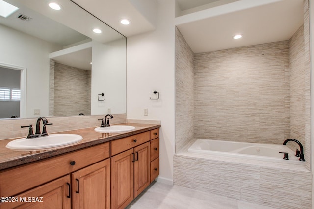 bathroom featuring tile patterned flooring, vanity, and tiled tub