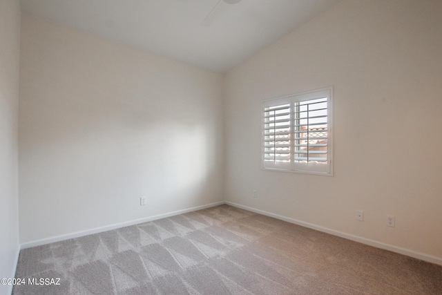 empty room featuring light colored carpet and vaulted ceiling