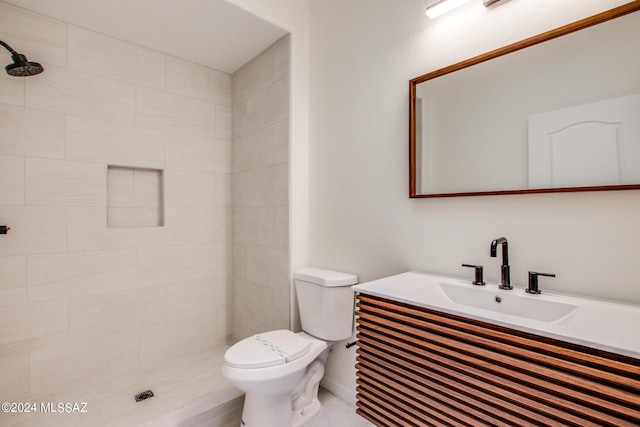 bathroom featuring tiled shower, vanity, and toilet