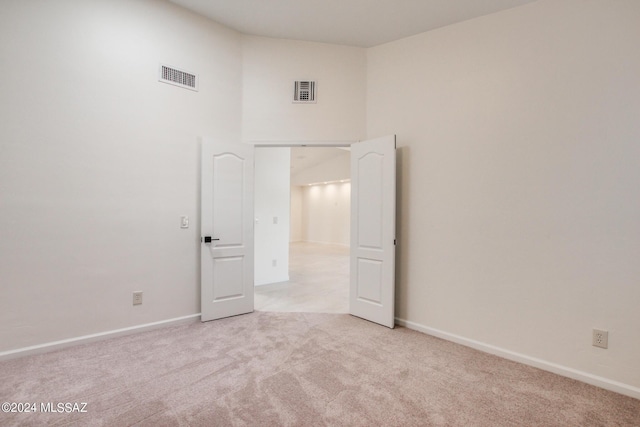 spare room with a towering ceiling and light colored carpet