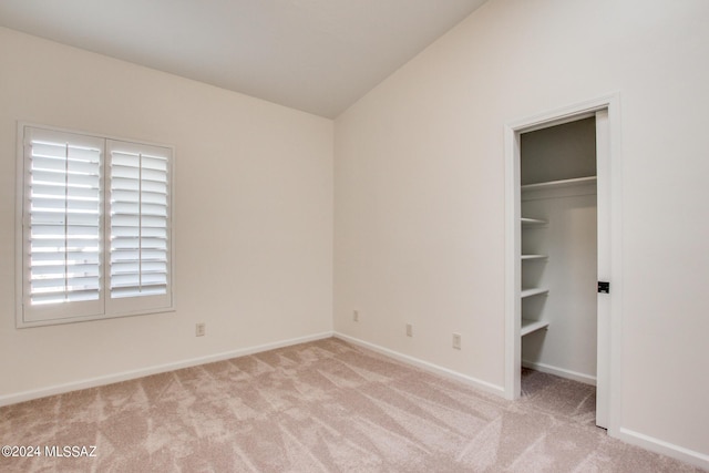 unfurnished bedroom featuring a closet, light colored carpet, and vaulted ceiling