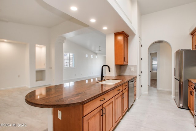 kitchen featuring kitchen peninsula, appliances with stainless steel finishes, ceiling fan, sink, and dark stone countertops