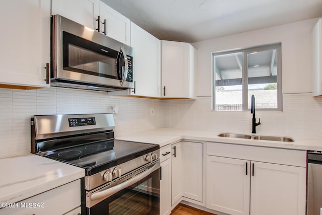 kitchen with white cabinets, sink, light stone countertops, and stainless steel appliances