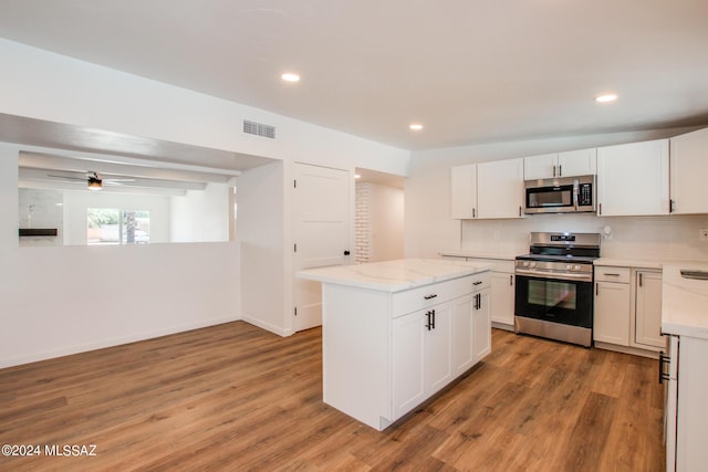 kitchen featuring stainless steel appliances, a kitchen island, light hardwood / wood-style flooring, backsplash, and white cabinets