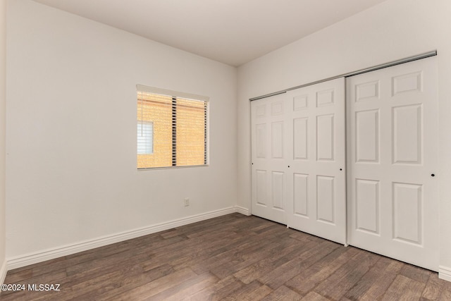 unfurnished bedroom with dark hardwood / wood-style flooring and a closet