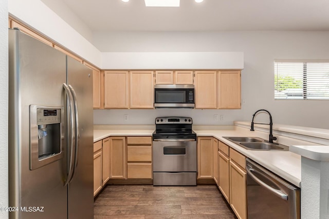 kitchen with sink, light brown cabinets, dark hardwood / wood-style floors, kitchen peninsula, and appliances with stainless steel finishes