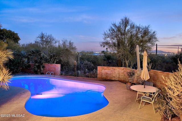 pool at dusk featuring a patio area