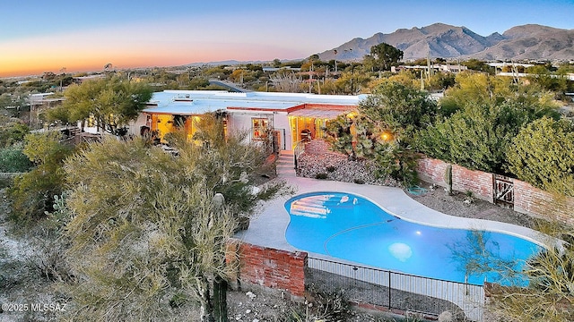 pool at dusk featuring a patio area and a mountain view