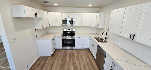 kitchen featuring white cabinetry, sink, stainless steel appliances, tasteful backsplash, and light stone counters