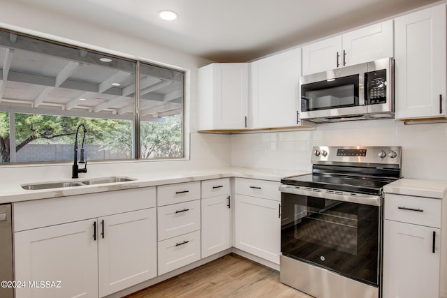 kitchen featuring white cabinetry, stainless steel appliances, a sink, and light countertops