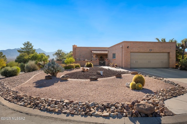 pueblo-style house with a garage and a mountain view