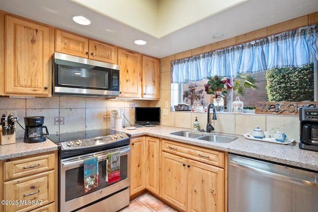 kitchen featuring light stone countertops, stainless steel appliances, backsplash, light tile patterned flooring, and sink