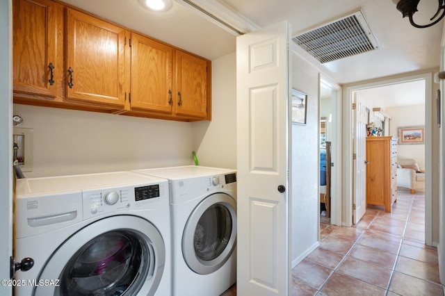 laundry room with washer and dryer, light tile patterned floors, and cabinets