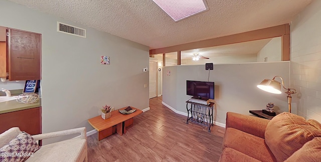 living room with a textured ceiling, light hardwood / wood-style flooring, and ceiling fan