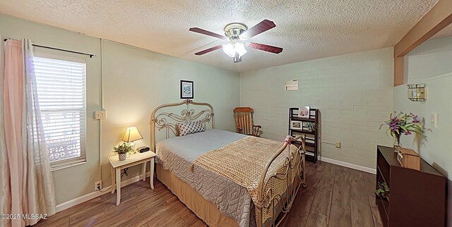 bedroom featuring a textured ceiling, ceiling fan, brick wall, and dark hardwood / wood-style floors