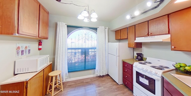 kitchen featuring white appliances, decorative light fixtures, a notable chandelier, and sink