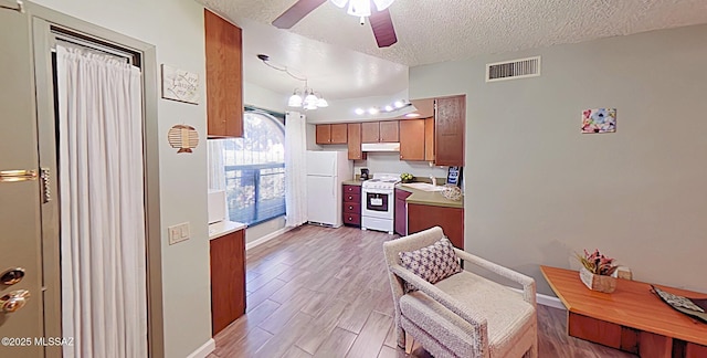 kitchen featuring ceiling fan with notable chandelier, a textured ceiling, white appliances, pendant lighting, and light hardwood / wood-style flooring