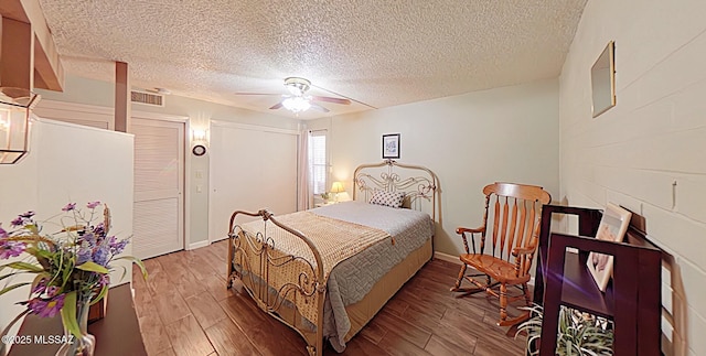 bedroom featuring hardwood / wood-style floors, ceiling fan, and a textured ceiling